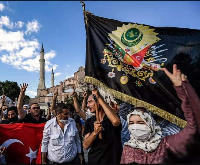 Gente ondea una bandera nacional turca y una bandera con el escudo de armas de Turquía del Imperio Otomano